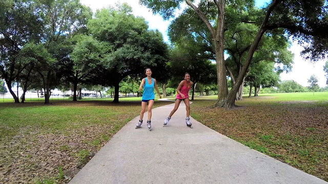 Young slim multi ethnic females inline skating in park