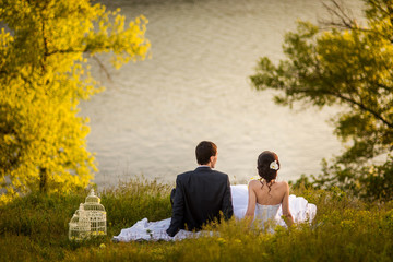 Fototapeta premium Wedding couple is sitting and looking water
