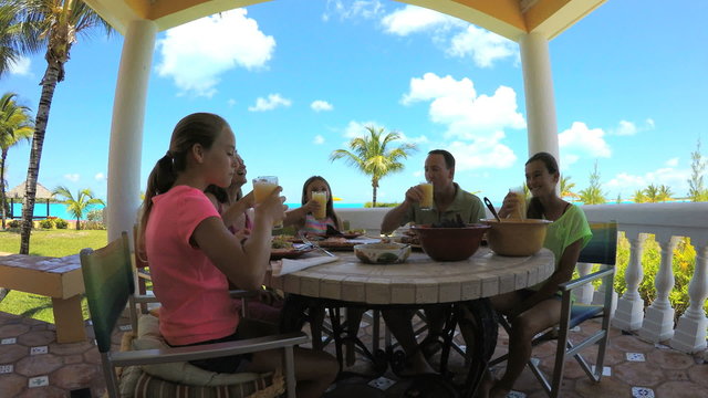 Young Caucasian family dining on vacation beach hotel decking