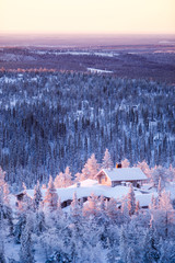 Winter scenery view over a cabin in frozen forest.