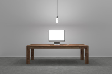 single computer screen on large desk with lamp hangig from ceili