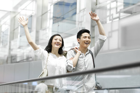 Young couple waving on escalator