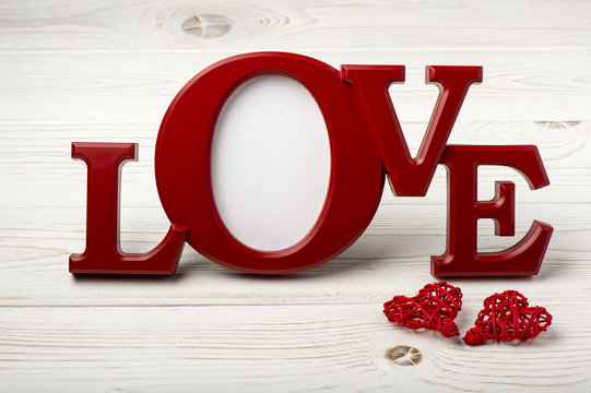 Red frame for pictures "love" on the wooden background.