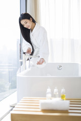 Young woman filling bathtub