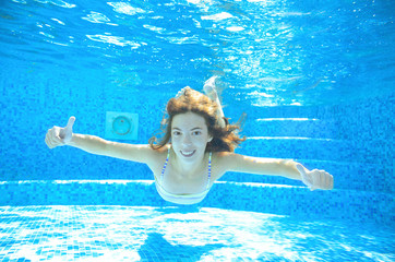 Child swims in pool underwater, happy active girl in goggles has fun under water, kid sport 
