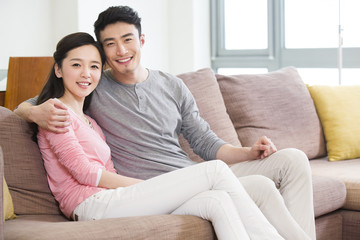 Happy young couple sitting on sofa