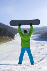 Rear view of a young man posing with his snowboard