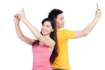 Young couple taking self-portrait shots with smart phones