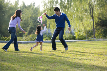 Fototapeta premium Young family flying a kite in the park