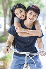 Obraz premium Young couple riding bicycle at campus