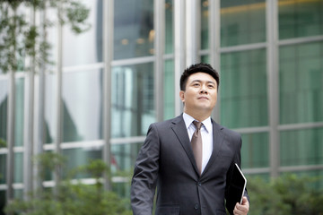 Confident mature businessman walking with digital tablet in hand, Hong Kong