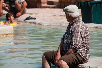 Old turkish man with hat sitting in hot spring