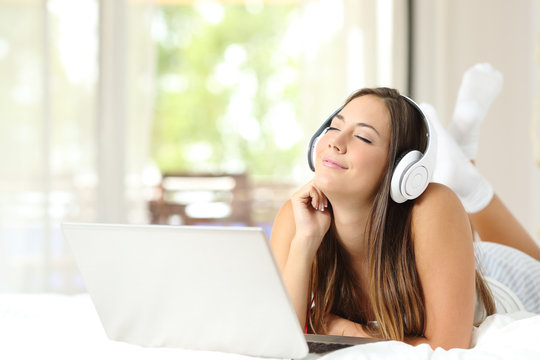 Girl listening music with headphones and laptop