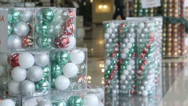 Christmas decorations for sale in shopping mall shoppers walking in background pan shot