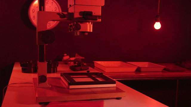 Photography darkroom with red lighting and equipment for film print processing