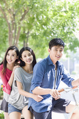 Young friends riding bicycle at campus