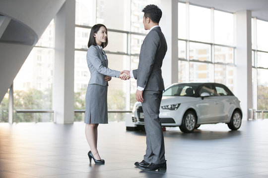Car saleswoman talking with customer