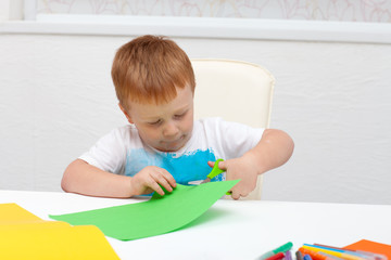 boy with scissors cuts paper