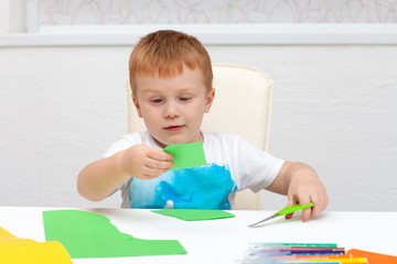 boy with scissors cuts paper