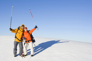 Two young people with their ski poles in the air