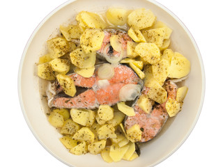 Top view of Salmon steaks in a frying pan with fried potatoes, onions and flavourings