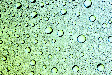 Water drops on transparent green glass surface.