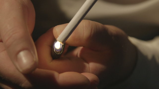 Man lights a cigarette with lighter in the dark close-up