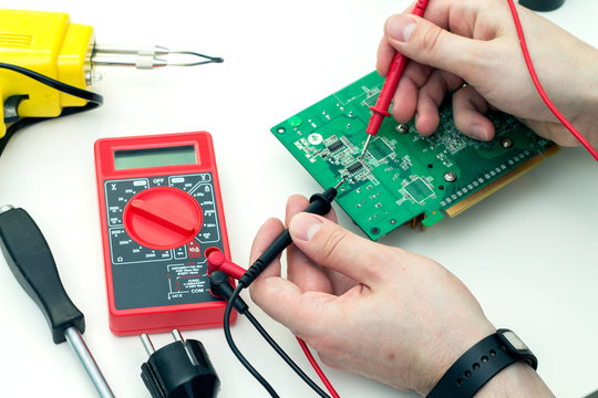 Electrician checks electronic hardware with a multimeter in the