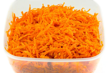 Salad of grated carrots in plastic container isolated on white
