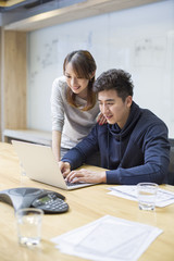 Business people using laptop in board room