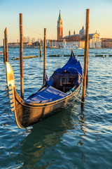 Gondolas moored by Saint Mark square with San Giorgio di Maggiore church in the background -...