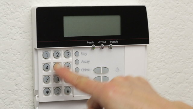 Female activates a home security system using its control panel. Includes audio of  the alarm panel generated noises.