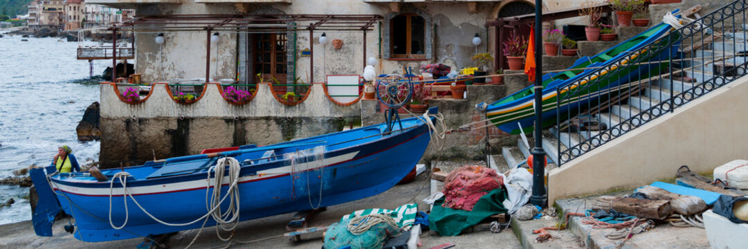 Two blue and green boats sitting on land in small italian town Scilla