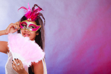 woman with carnival mask holds fan
