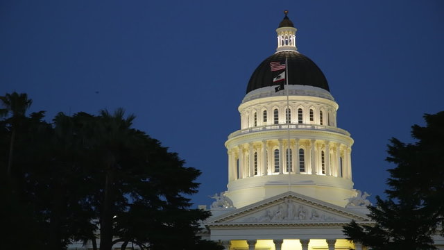 Panning and locked down clip of the rotunda and dome of the state capitol building in Sacramento, California at dusk. 