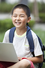 Happy schoolboy using high-tech laptop