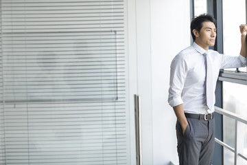 Young businessman looking through window