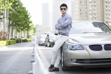 Naklejka premium Young man leaning against his car