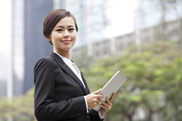 Professional businesswoman looking over shoulder with digital tablet in hand, Hong Kong