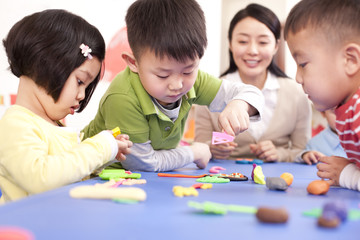 Obraz premium Kindergarten teacher and children playing with plasticine