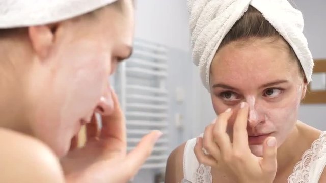 Woman applying mask cream on face in bathroom 4K