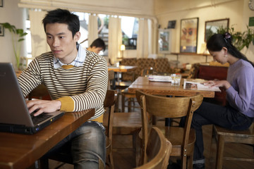 Young Man Sitting In Cafe On Laptop Computer