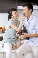 Woman feeding man grapes in the kitchen