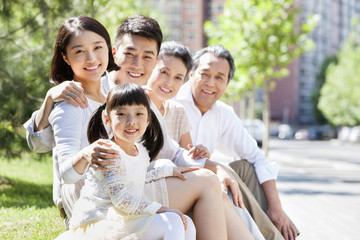 Happy family sitting in a row outdoors