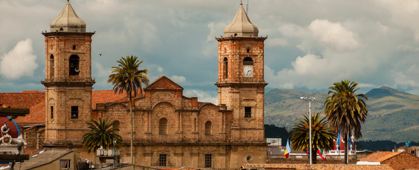Old colonial stone church with roofs and palm tree near Bogota