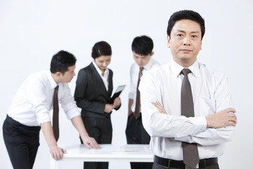 Mature businessman with his colleagues being busy at work in background