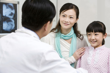 Doctor speaking with his  young patient and her mother