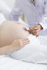 Fototapeta na wymiar Doctor examining pregnant woman at home