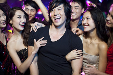 Young man surrounding by beautiful women in nightclub