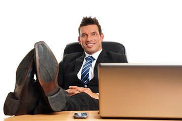 Handsome businessman in suit with feet on desk and relaxes